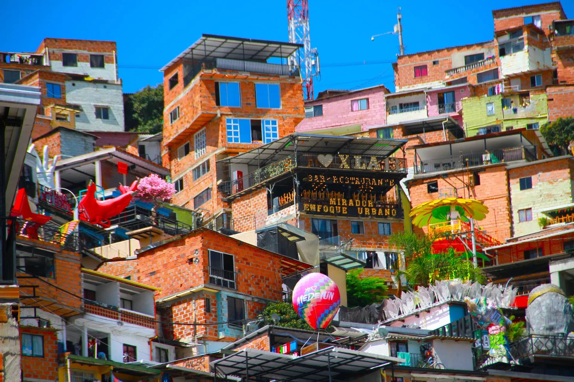 Large colorful mural above the outdoor escalators on a hillside street in Comuna 13, Medellín