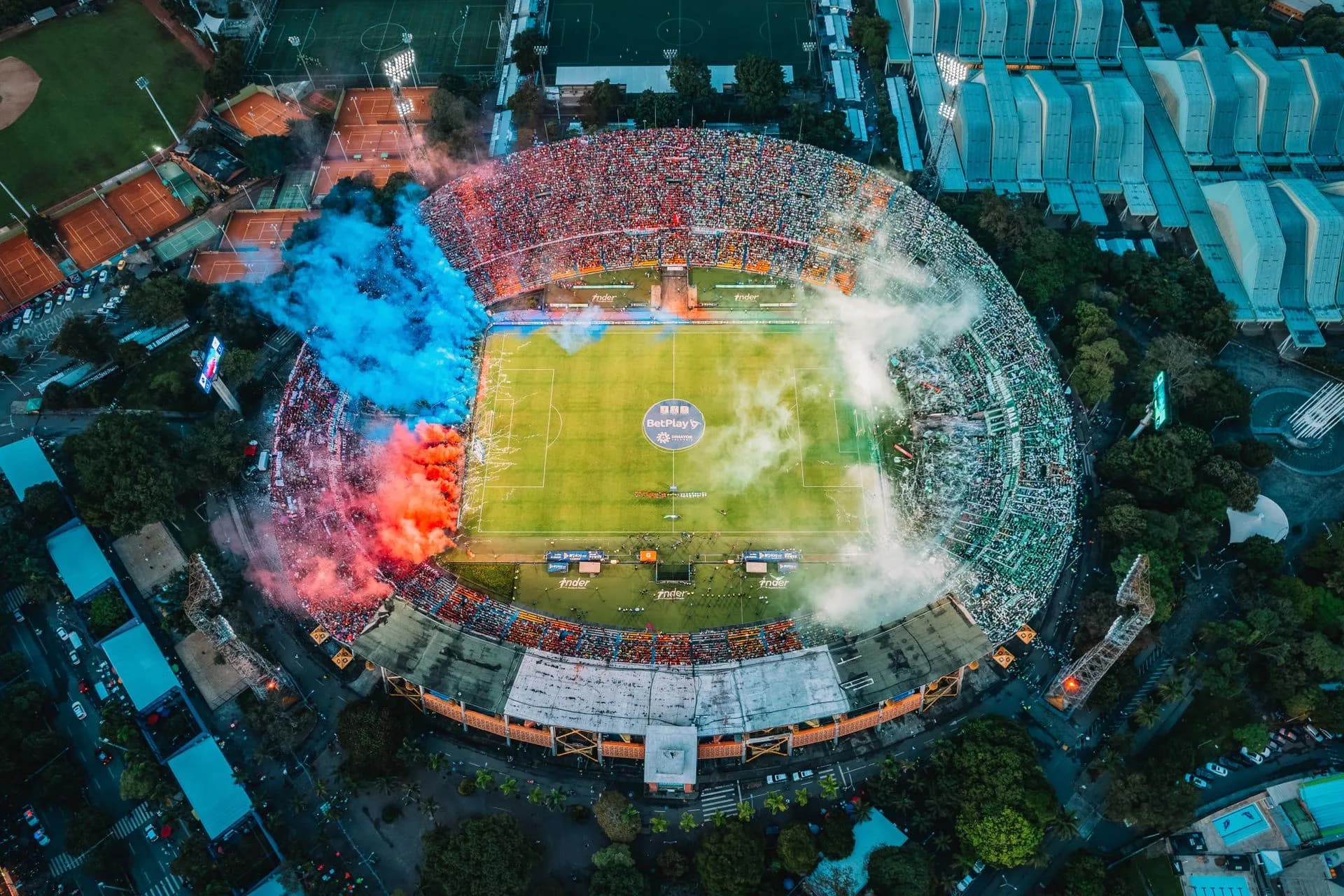 Fans with flags and green smoke filling the stands at Estadio Atanasio Girardot in Medellín
