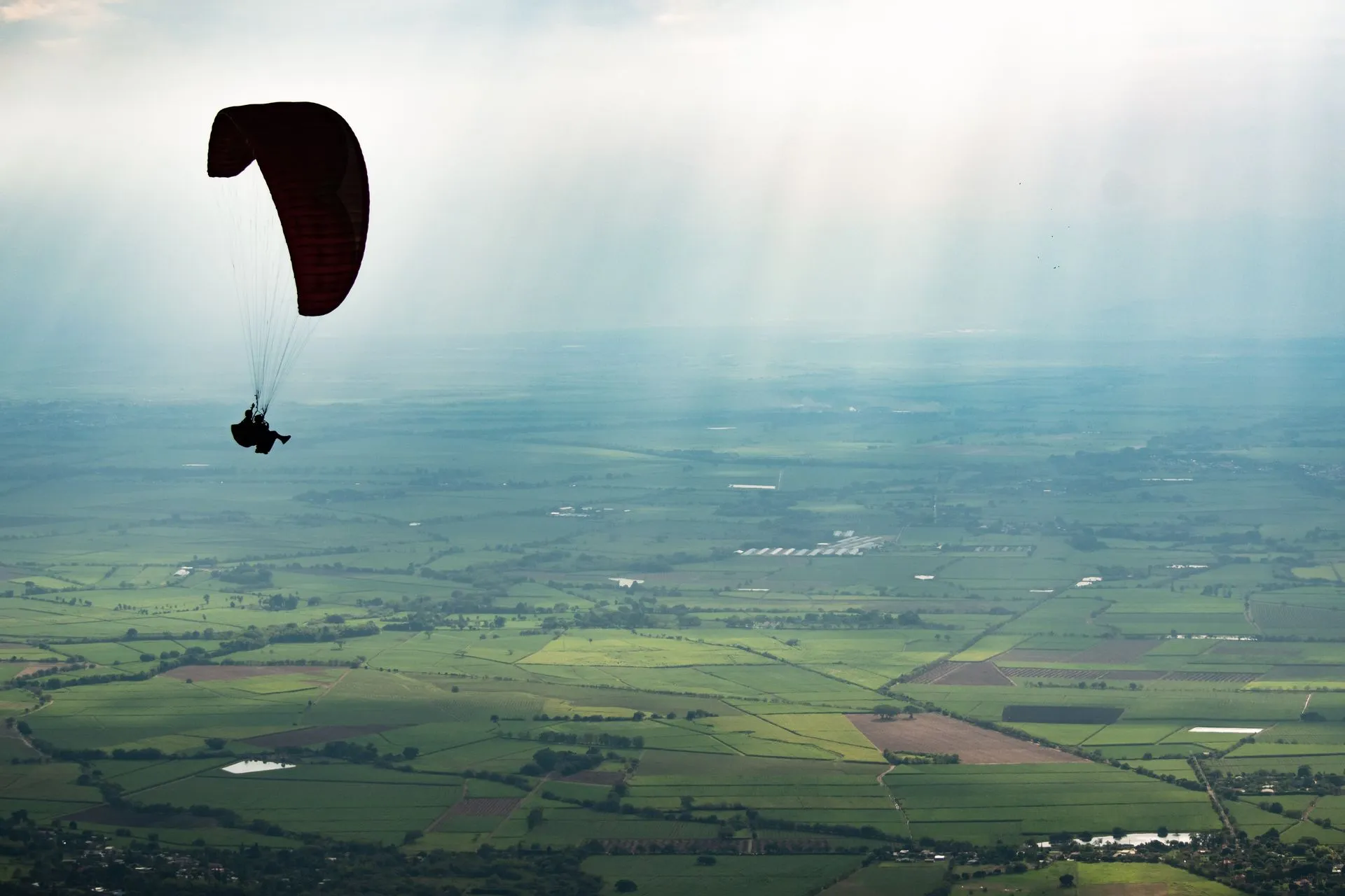 Tandem paraglider soaring above the green hills of the Aburrá Valley outside Medellín