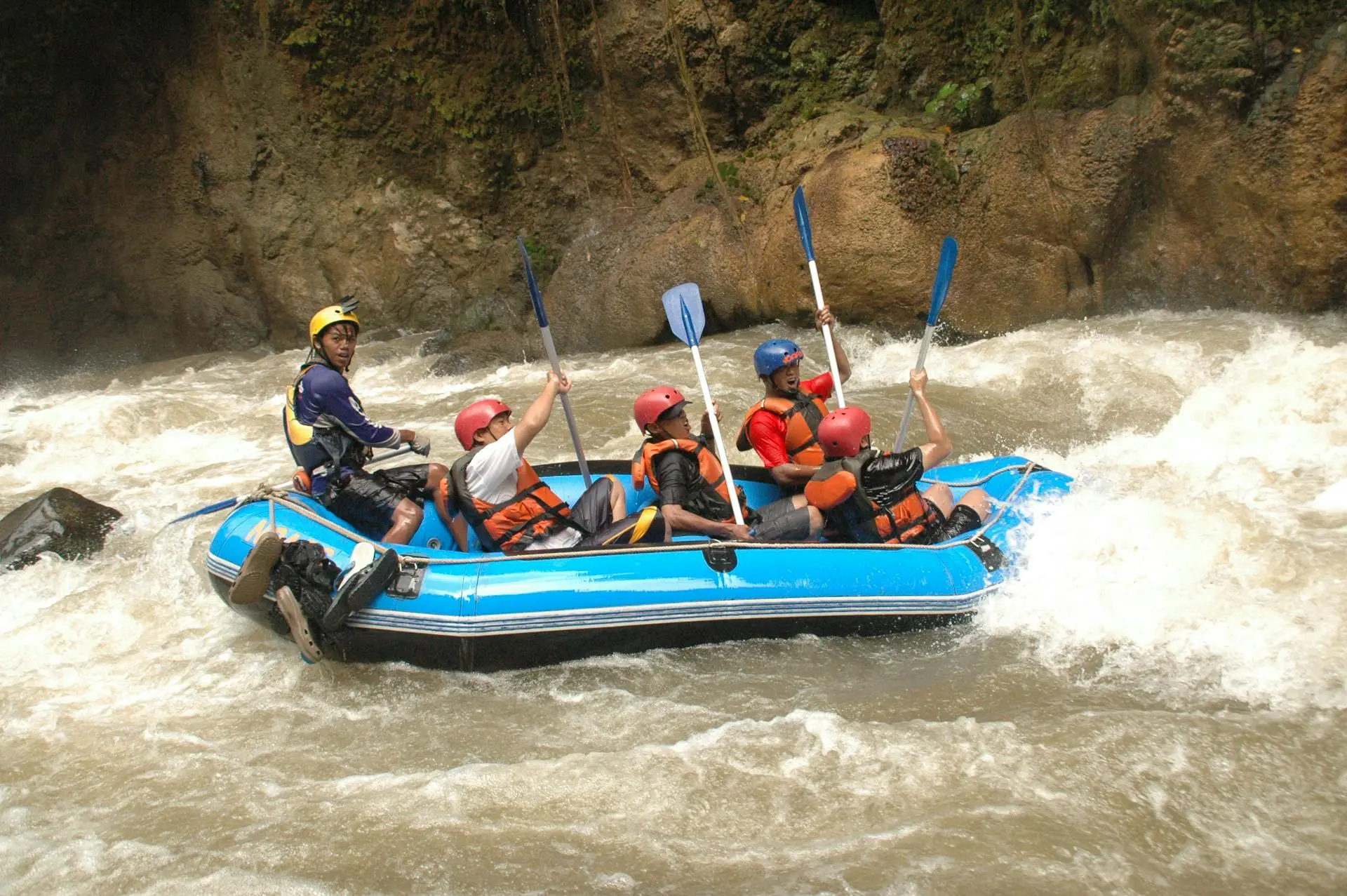 Raft dropping through a whitewater rapid between jungle boulders on the Río Calderas in Antioquia
