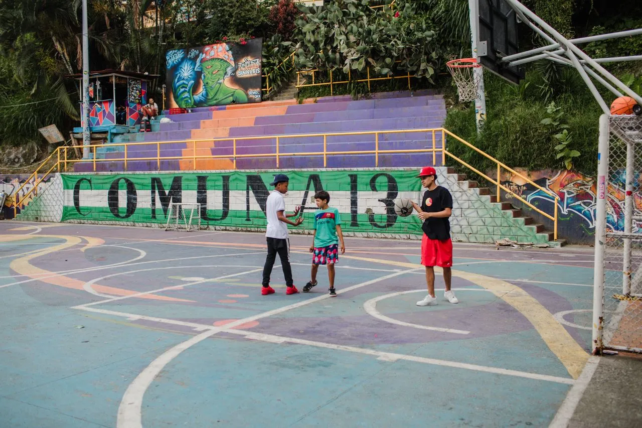 Mural-covered basketball court surrounded by hillside houses in Comuna 13, Medellín