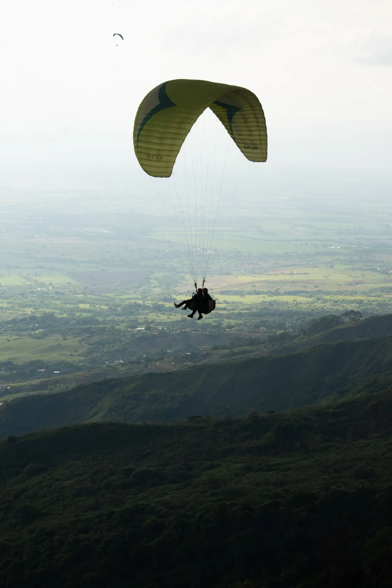 Tandem paraglider lifting off the ramp and climbing above the hills outside Medellín, Colombia